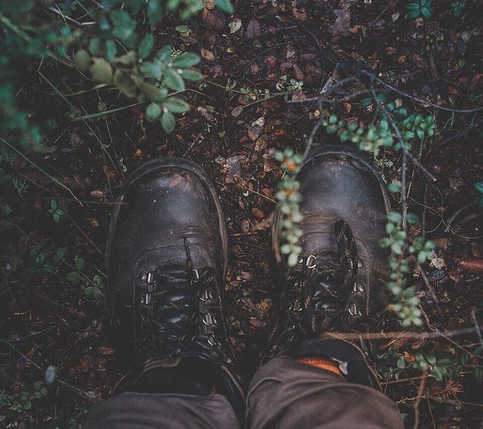 Feet in hiking boots against a lush forest floor